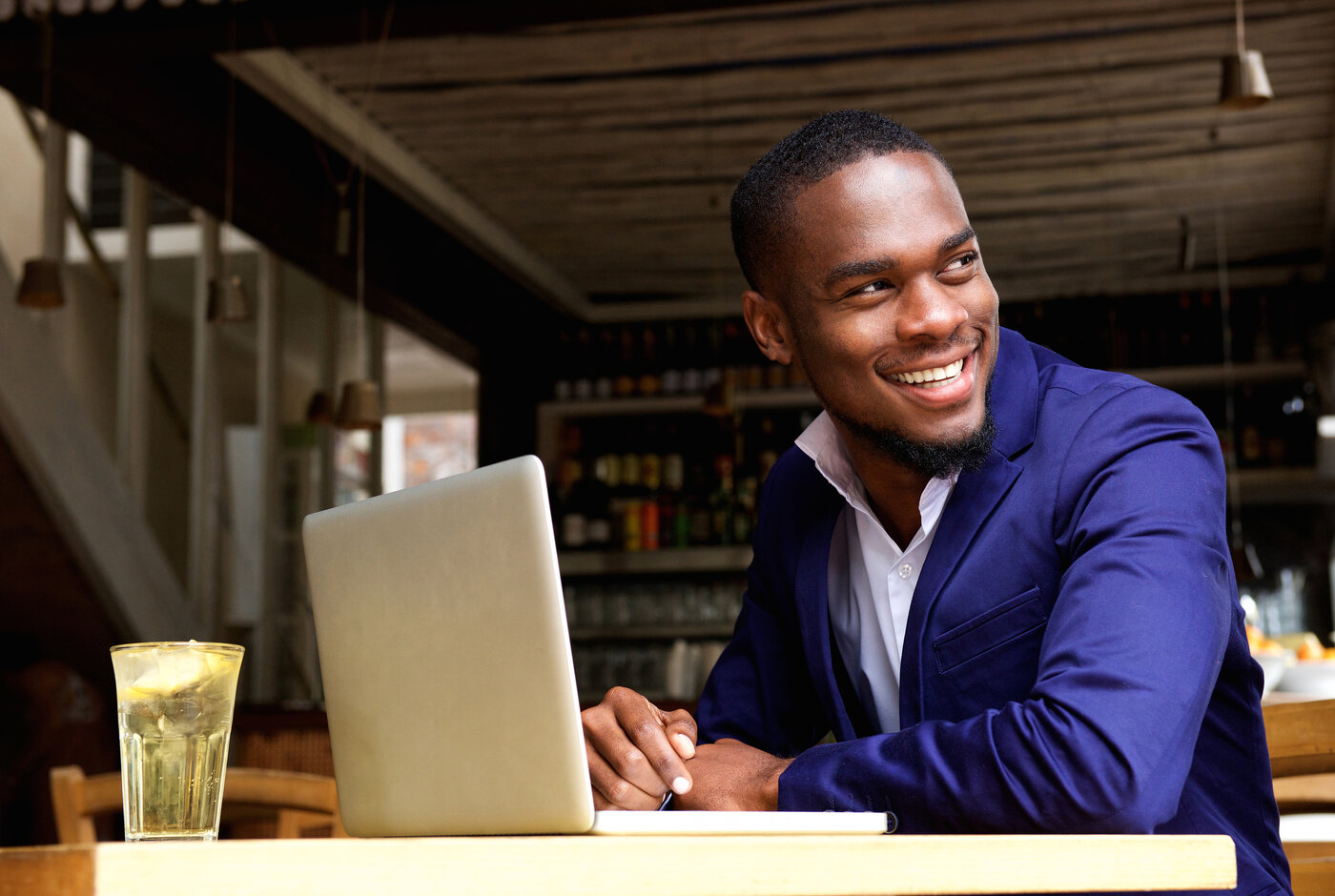 Portrait of a smiling black businessman with laptop at cafe